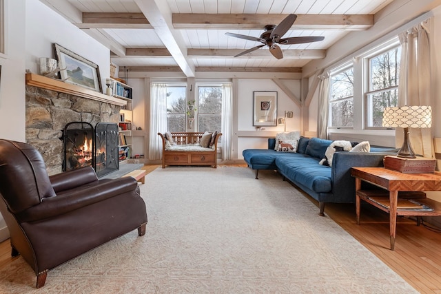 living room featuring beam ceiling, ceiling fan, a fireplace, and light hardwood / wood-style floors