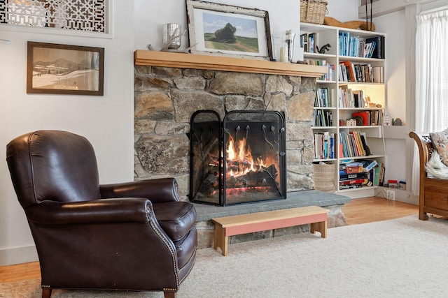 sitting room featuring a stone fireplace and hardwood / wood-style flooring