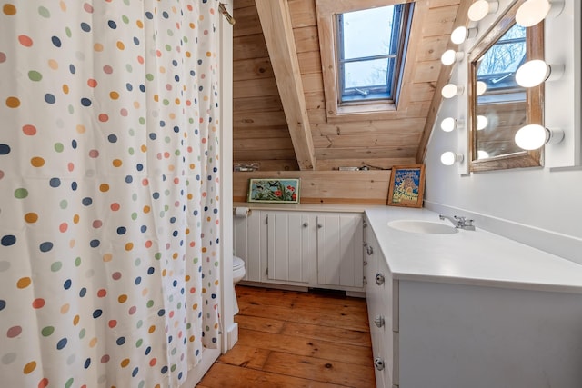 bathroom featuring lofted ceiling with skylight, wooden walls, hardwood / wood-style flooring, vanity, and wood ceiling