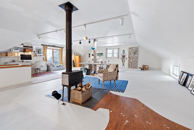 living room with a healthy amount of sunlight, lofted ceiling, a wood stove, and track lighting