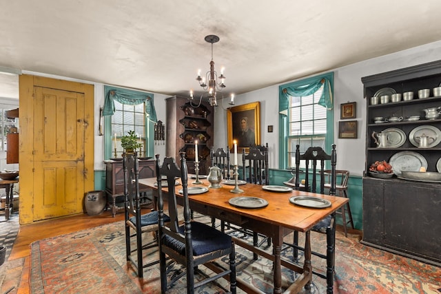 dining space featuring wood-type flooring and a notable chandelier