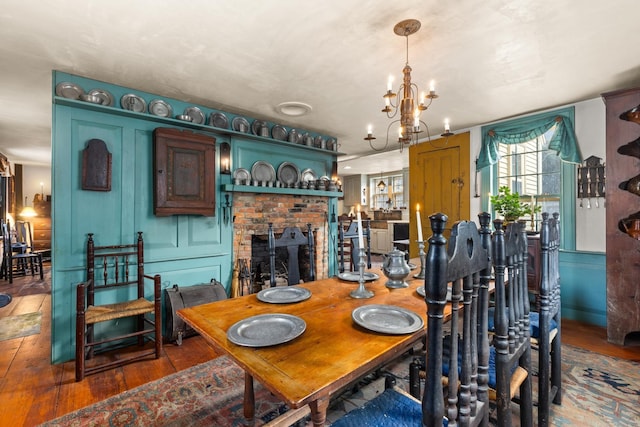 dining room featuring a brick fireplace, dark hardwood / wood-style floors, and a chandelier