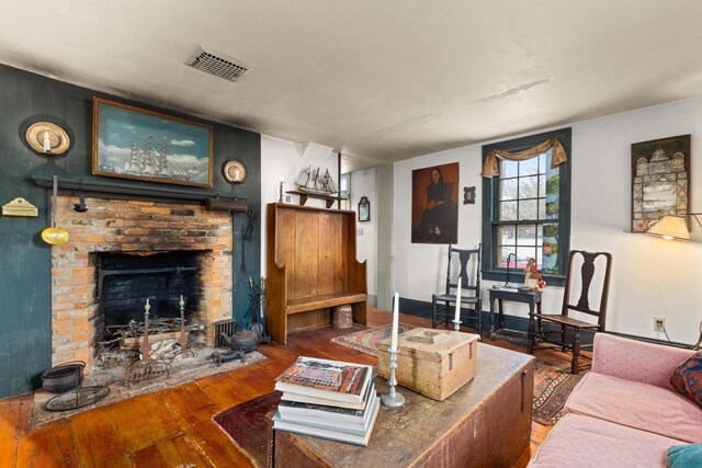 living room with a brick fireplace and hardwood / wood-style flooring