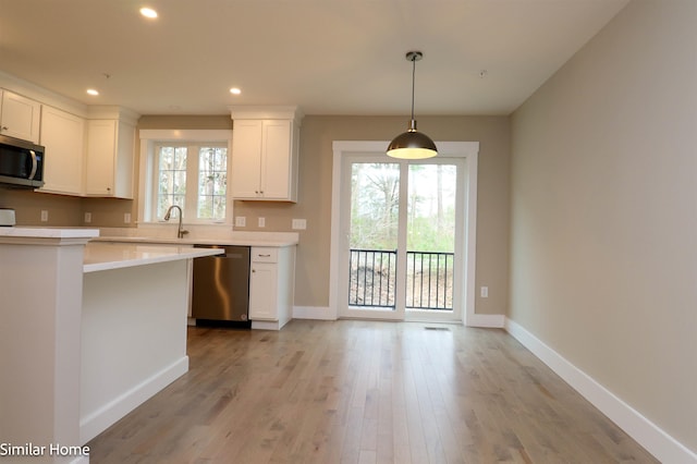 kitchen featuring hanging light fixtures, stainless steel appliances, light hardwood / wood-style floors, and white cabinets