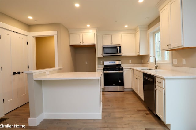 kitchen featuring appliances with stainless steel finishes, sink, a kitchen island, and white cabinets