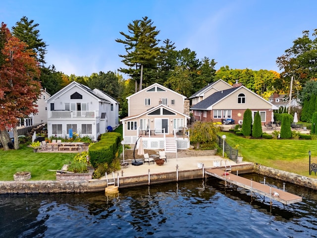 rear view of house featuring a deck with water view, a patio area, a balcony, and a lawn