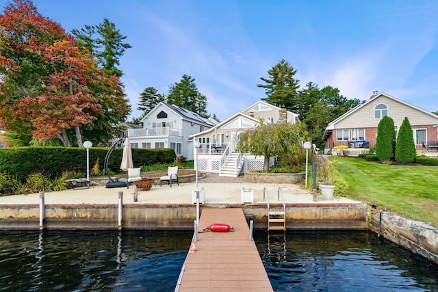 view of dock featuring a deck with water view and a yard