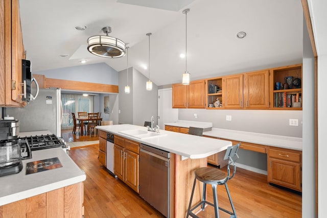 kitchen with built in desk, pendant lighting, sink, a kitchen island with sink, and stainless steel appliances