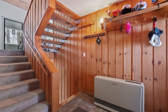 staircase featuring heating unit and wood walls