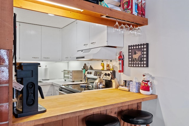 kitchen featuring electric stove, pendant lighting, and white cabinetry