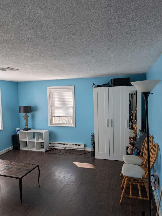 sitting room featuring hardwood / wood-style flooring, a baseboard radiator, and a textured ceiling