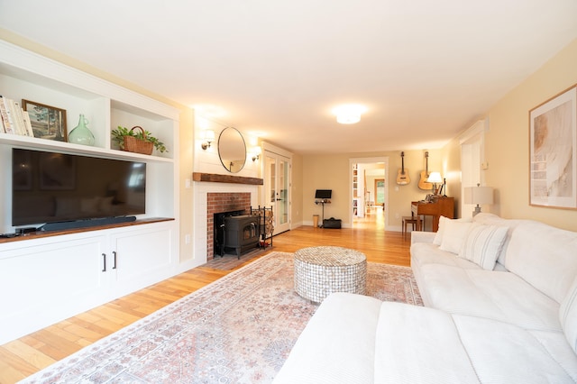 living room featuring a wood stove, built in features, and light wood-type flooring