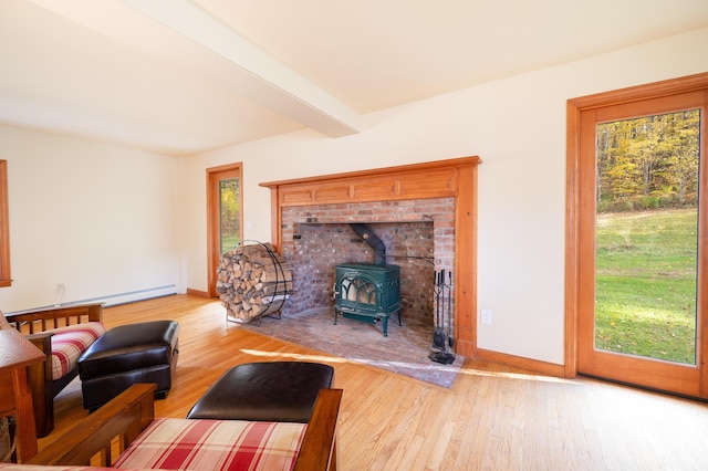 living room with beamed ceiling, light hardwood / wood-style flooring, and a wood stove