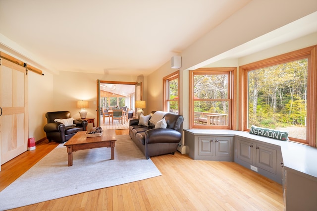 living room featuring a barn door, baseboard heating, and light hardwood / wood-style flooring