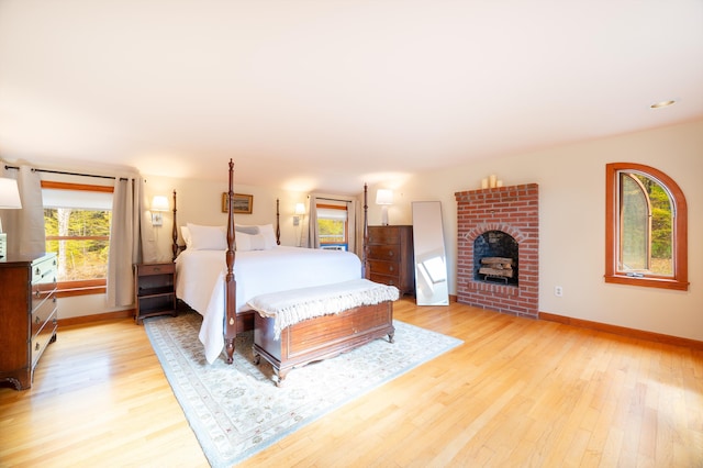 bedroom with a fireplace and light wood-type flooring