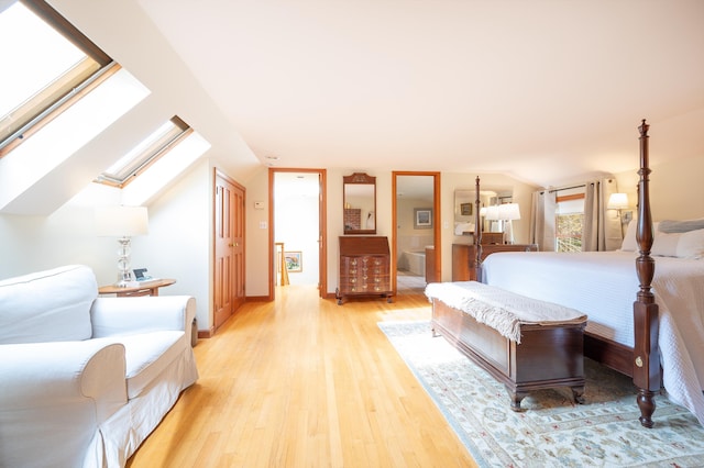 bedroom featuring lofted ceiling with skylight and light hardwood / wood-style floors