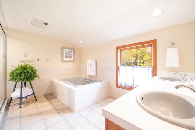 bathroom featuring a relaxing tiled tub, lofted ceiling, vanity, and tile patterned flooring