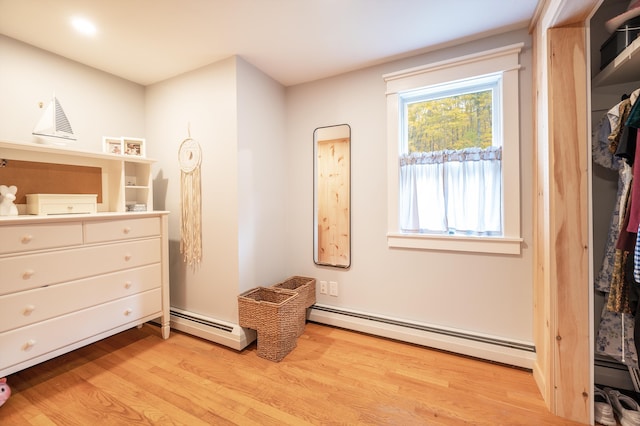 bedroom with light hardwood / wood-style flooring and a baseboard heating unit