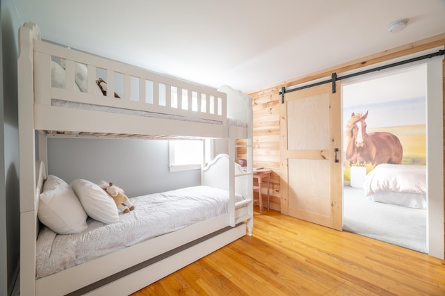 bedroom with wood-type flooring and a barn door