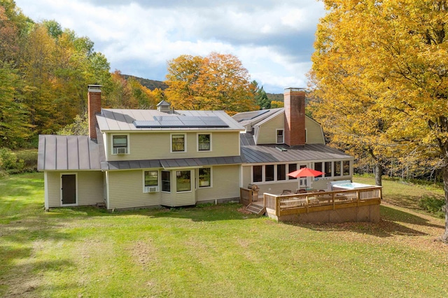 back of property featuring a wooden deck, a yard, and solar panels