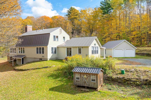 back of house with a garage, a yard, and a storage shed