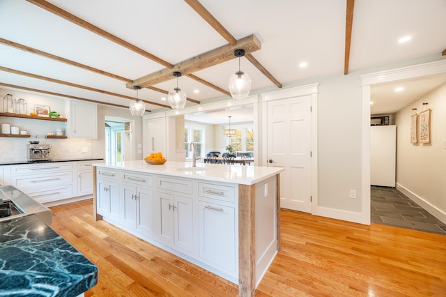 kitchen featuring white cabinetry, a kitchen island, pendant lighting, and light wood-type flooring