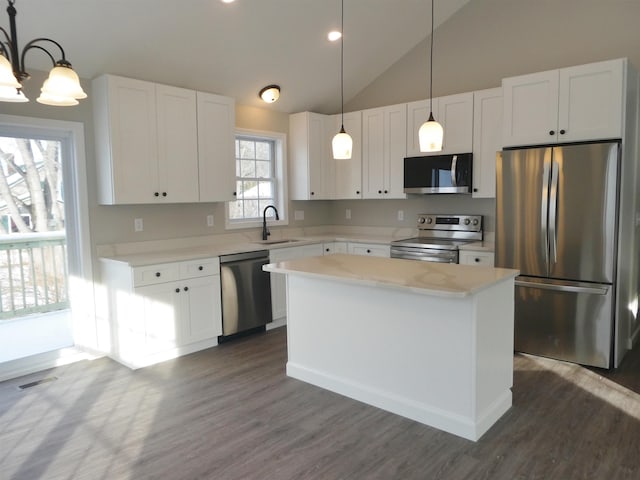 kitchen featuring stainless steel appliances, decorative light fixtures, sink, and a kitchen island