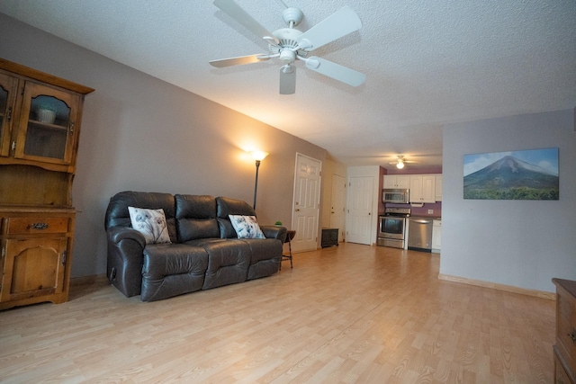 living room featuring ceiling fan, a textured ceiling, and light hardwood / wood-style floors