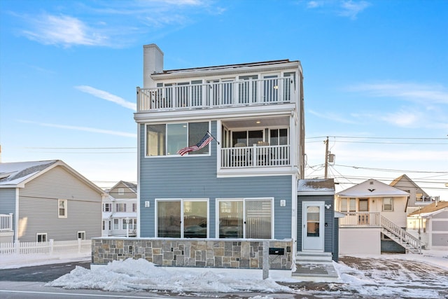 snow covered rear of property with a balcony