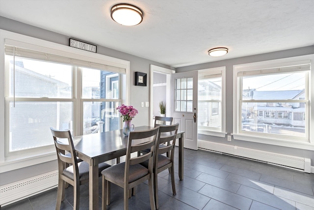 tiled dining space featuring a baseboard heating unit and a textured ceiling