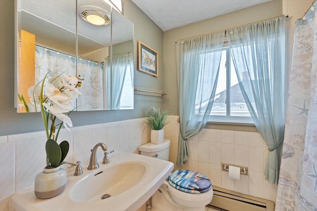 bathroom with sink, tile walls, baseboard heating, and toilet