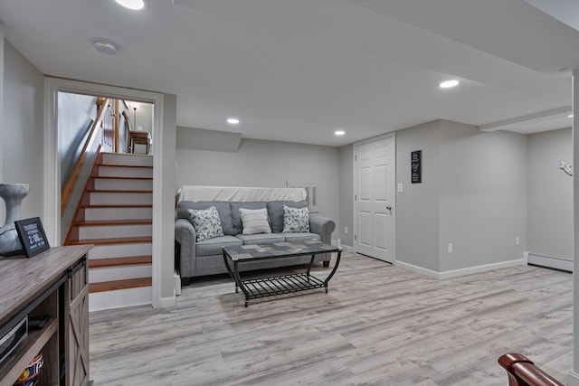 living room with a baseboard heating unit and light hardwood / wood-style floors