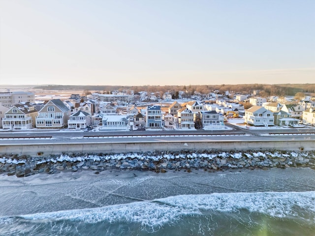 aerial view at dusk featuring a water view and a view of the beach