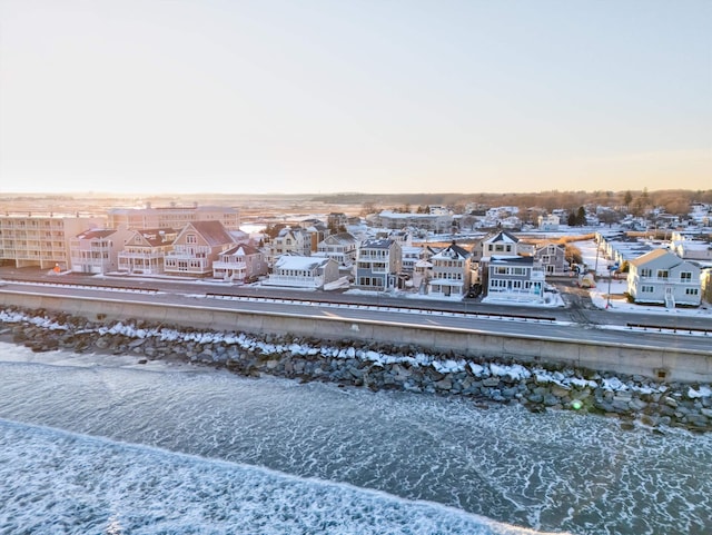 aerial view at dusk featuring a water view and a beach view