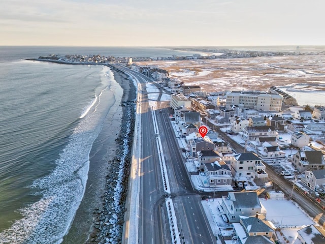 aerial view at dusk featuring a water view and a beach view