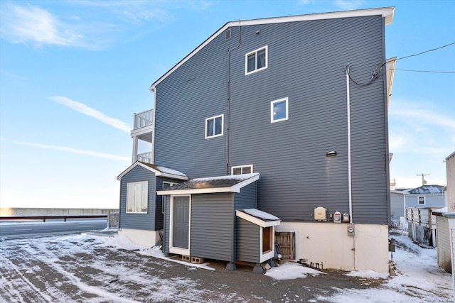 snow covered rear of property with a balcony