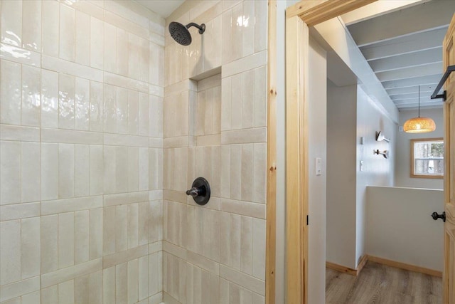 bathroom featuring hardwood / wood-style floors, beamed ceiling, and tiled shower