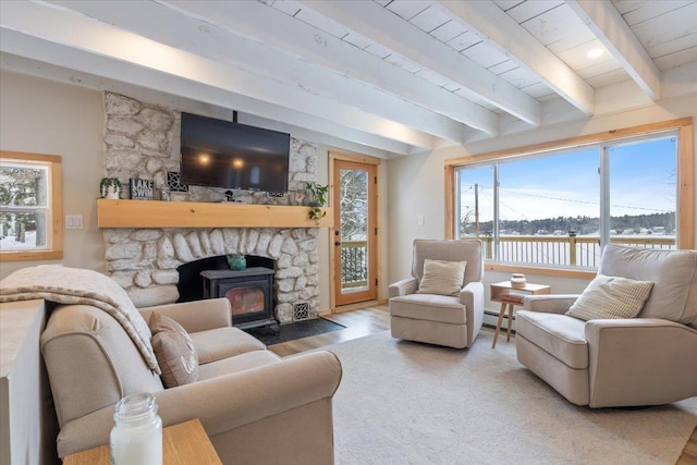 living room with wood-type flooring, a stone fireplace, beam ceiling, and baseboard heating