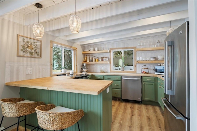 kitchen featuring appliances with stainless steel finishes, butcher block counters, green cabinetry, a kitchen bar, and kitchen peninsula