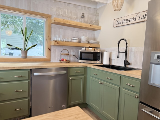 kitchen featuring appliances with stainless steel finishes, sink, green cabinets, and butcher block countertops