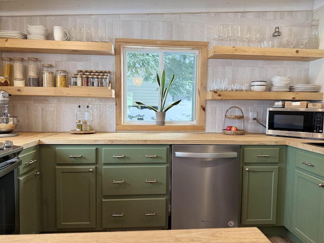 kitchen with butcher block counters, backsplash, green cabinets, and appliances with stainless steel finishes