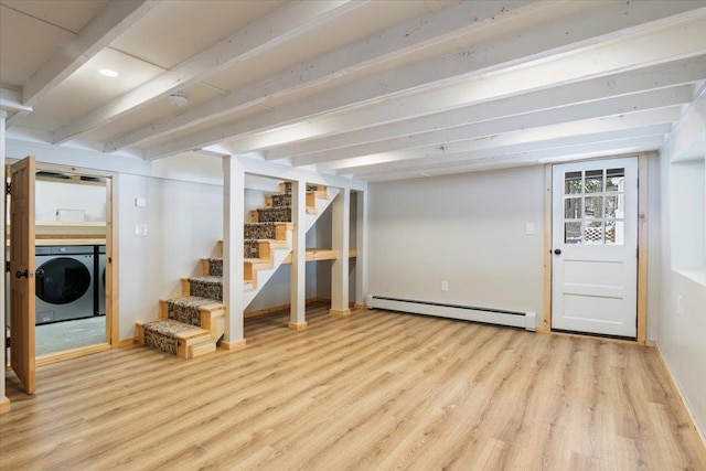 basement featuring baseboard heating, washer and clothes dryer, and light hardwood / wood-style flooring