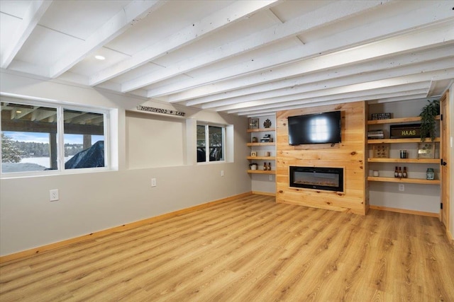 unfurnished living room with light wood-type flooring, beam ceiling, and built in shelves