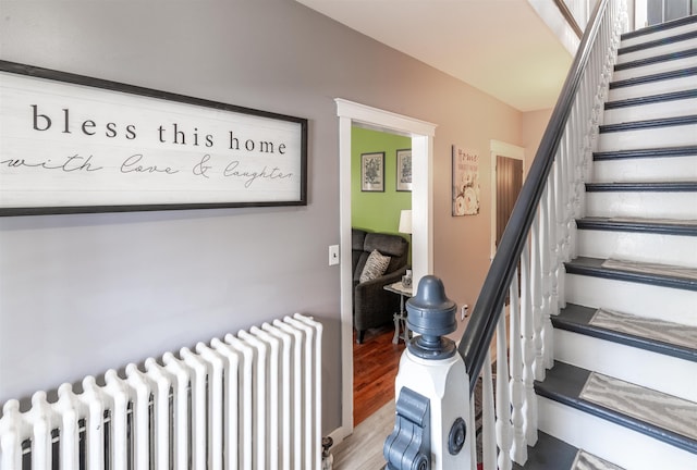 stairway with hardwood / wood-style flooring and radiator heating unit