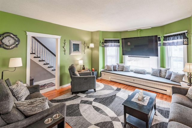 living room with hardwood / wood-style flooring, a baseboard radiator, and a healthy amount of sunlight