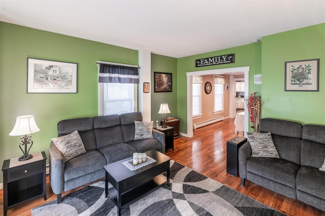 living room featuring wood-type flooring, a wealth of natural light, and baseboard heating