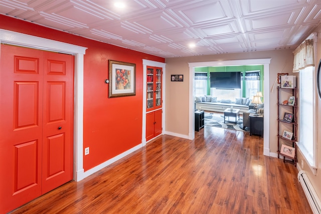 corridor with hardwood / wood-style floors and baseboard heating