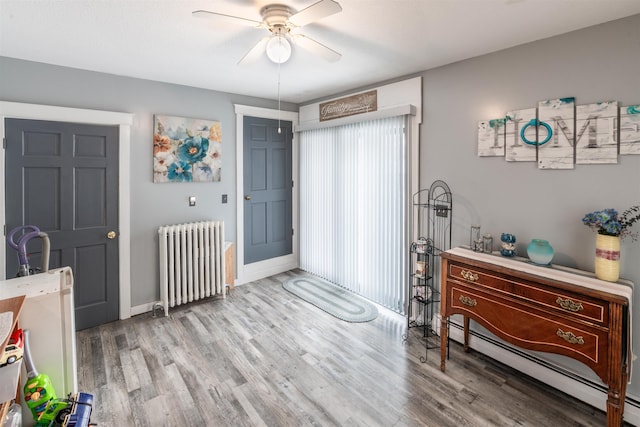 foyer entrance with ceiling fan, radiator heating unit, baseboard heating, and light hardwood / wood-style flooring