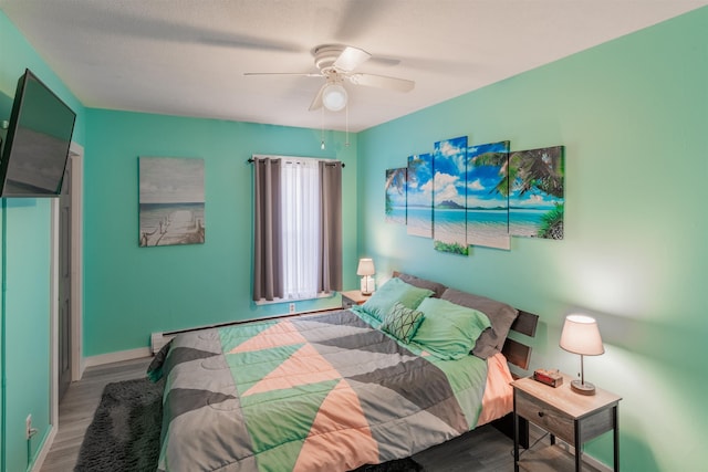 bedroom featuring hardwood / wood-style floors, ceiling fan, and a baseboard heating unit