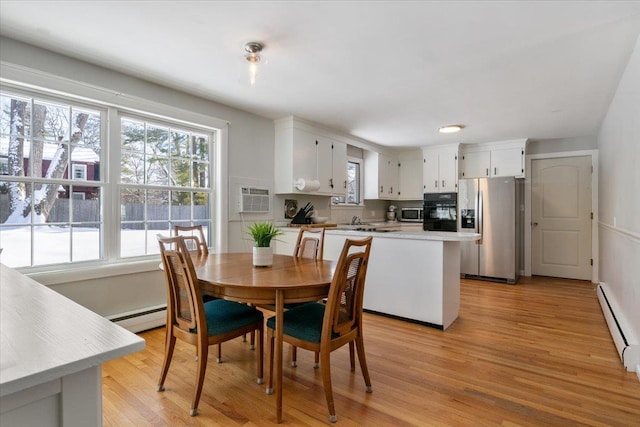 dining area with light hardwood / wood-style flooring, a wealth of natural light, and baseboard heating